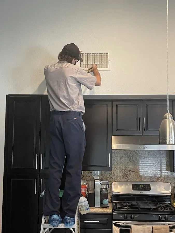Technician inspecting an air vent during HVAC service in Riverside